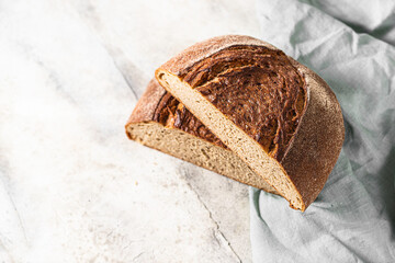 Freshly baked rye bread on a light concrete background, linen napkin. Place for your text. Freshly baked sourdough bread. Pastry items.