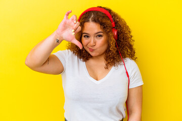 Young latin curvy woman listening music isolated on yellow background showing a dislike gesture, thumbs down. Disagreement concept.