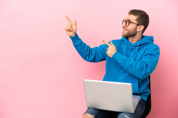 Young man sitting on a chair with laptop pointing with the index finger a great idea