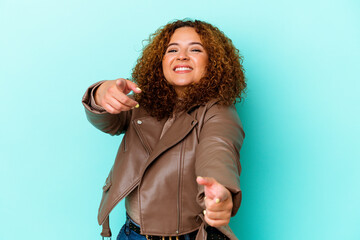 Young latin curvy woman isolated on blue background cheerful smiles pointing to front.
