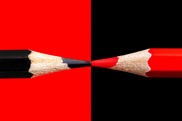 Black and red pencils on a black-red background closeup