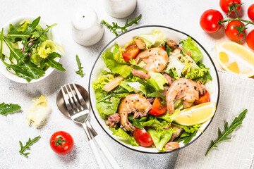 Healthy green Seafood salad with fresh leaves, tomatoes and fried seafood. Top view at white stone table.