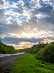 Fototapeta na wymiar Country road with markings in the middle of the forest. Path and forward movement in the sun. Beautiful, green forest in the spring at sunset. Concept for success in the future goal and passing time