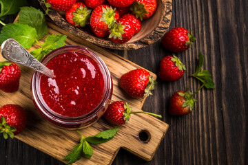 Strawberry jam in the glass jar with fresh berries at wooden table. Top view image with copy space.