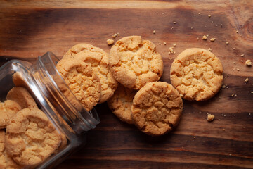Close-up of delicious freshly baked simple cookies or biscuits coming out from a glass jar . over a...