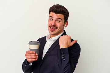 Young business caucasian man wearing wireless headphones and holding take way coffee isolated on white background points with thumb finger away, laughing and carefree.