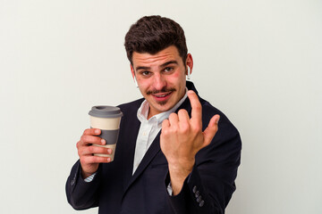 Young business caucasian man wearing wireless headphones and holding take way coffee isolated on white background pointing with finger at you as if inviting come closer.