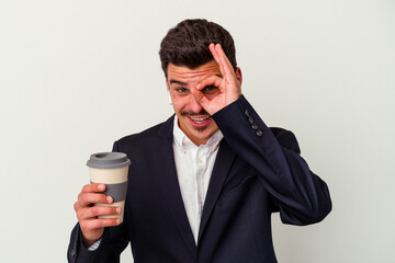 Young business caucasian man wearing wireless headphones and holding take way coffee isolated on white background excited keeping ok gesture on eye.