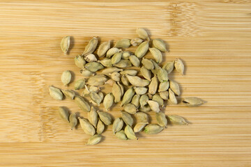 Fresh tasty spices, soft green cardamon Top view close up on bamboo cutting board