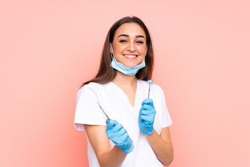 Woman dentist holding tools isolated on pink background