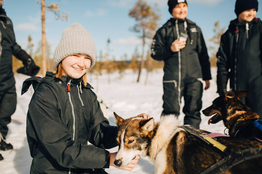Portrait of smiling teenage girl stroking husky dog during winter