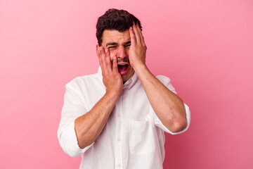 Young caucasian man isolated on pink background whining and crying disconsolately.