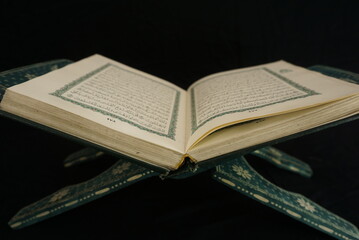 Photo of an open Islamic holy book against a black background and incoming light. suitable as a photo with the theme of religion and events of Islam or Ramadan