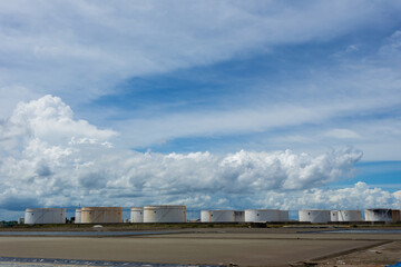 Fototapeta premium Oil tanks in a row under blue sky, Large white industrial tank for petrol, oil refinery plant. Energy and power