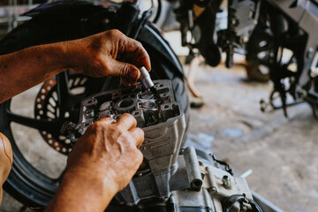 Assembling the cylinder head on a motorcycle engine by an engine mechanic.