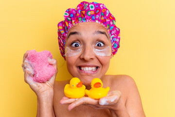 Young mixed race woman taking a bath holding a sponge and rubber ducks