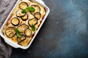 Greek mediterranean dish Moussaka with baked eggplants, ground beef in white ceramic casserole on rustic stone background from above, traditional dish of Greece, space for text