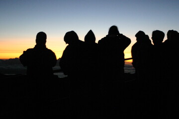 Fototapeta premium Mount Haleakala Maui, Hawaii, with Cloudy Sunrise with People Enjoying the View with Silhouettes starting a new Day