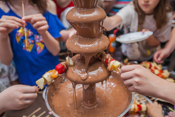 Fototapeta na wymiar Chocolate fountain at kids birthday party, topping chocolate