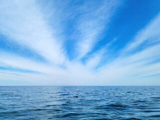 white wispy cirrus cloud burst pattern in blue sky over calm Lake Michigan water