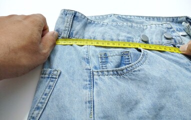 Hand jeans are pulling the yellow tape measure.  Give an idea of ​​measuring the waist circumference, cut out the clothes