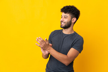 Young Moroccan man isolated on yellow background applauding