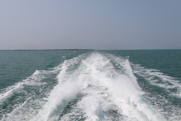 Ship wake on the ocean.aves from the back of a speed boat over the water's surface in sea. Waves behind a boat on a clear blue sea