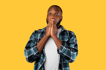 Shocked Black Millennial Male Covering Mouth Posing On Yellow Background