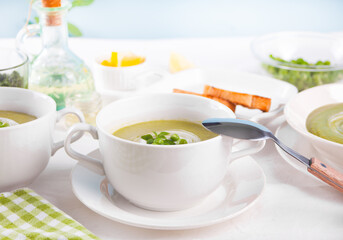 Delicious vegetable soup with potato, broccoli, green pea and spinach on the dinner table