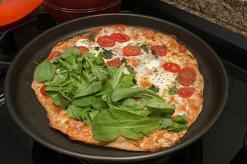 Homemade Pizza Margarita with Mozzarella Cheese, Tomatoes, Basil, Oregano Topped with Arugula and Watercress