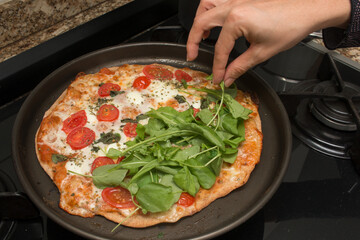 Homemade Pizza Margarita with Mozzarella Cheese, Tomatoes, Basil, Oregano Topped with Arugula and Watercress