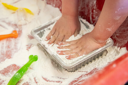 Experiments Close Up Shot Of The Small Puffy Hands Of A Young Kindergarten Child Playing With Flour In An Indoor Play Area, Experimenting.