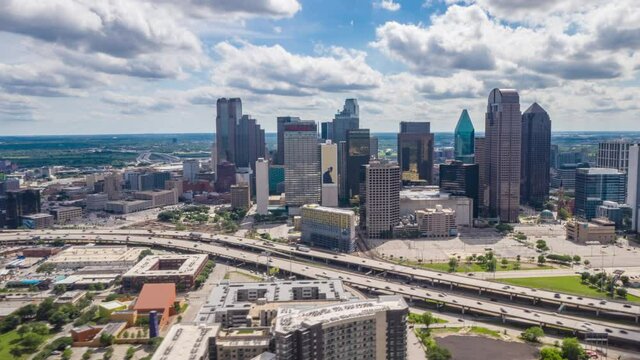 Stunning aerial hyper lapse footage of downtown area in Dallas, USA. Drone moving towards modern tall multi story commercial buildings behind rush highway.