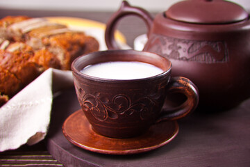 Clay tea cup with teapot on old wooden table