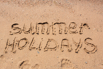 Words Summer holidays handwritten on a sandy beach