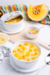 Millet porridge with pumpkin slices in light forms for baking on a light background. Vegetarian diet. Traditional autumn cuisine.