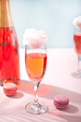 Glasses with sweet cotton candy pink cocktail and bottle on background