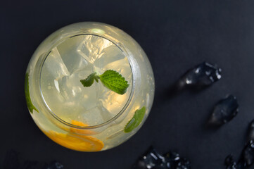 Cocktail with mint, citrus and ice, top view on a black background. Summer refreshing drink mojito