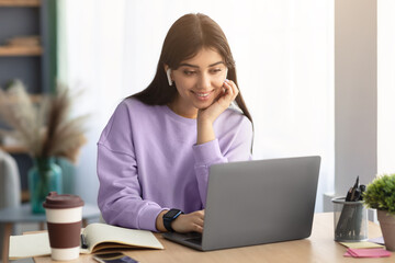 Woman sitting at desk, using computer and watching video