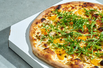 Appetizing pizza with creamy sauce, chicken, yellow tomatoes, capers. crisp sides. Hard light. Gray background.