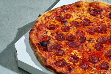 Delicious pizza with spicy chorizo salami and pepper, tomato sauce and crispy sides. Hard light. Gray background