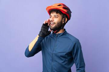 Young Moroccan cyclist man isolated on purple background shouting with mouth wide open to the side - obrazy, fototapety, plakaty