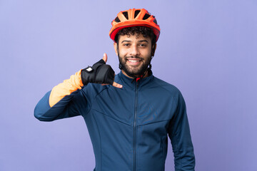 Young Moroccan cyclist man isolated on purple background making phone gesture. Call me back sign - obrazy, fototapety, plakaty