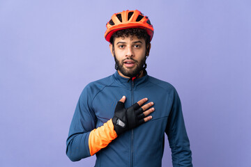 Young Moroccan cyclist man isolated on purple background surprised and shocked while looking right - obrazy, fototapety, plakaty