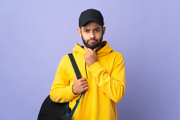 Young sport Moroccan man with sport bag isolated on purple background thinking