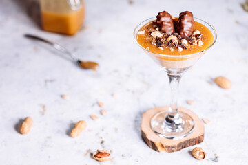 Dessert with caramel, peanut, mascarpone, hazel butter and cookies served in a cocktail glass