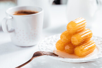 Turkish dessert called Tulumba served on a white background with Turkish coffee