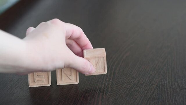 A female hand builds word envy with wooden cubes. Concept