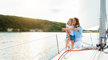 Naklejka premium Cheerful Mother And Daughter Enjoying Sailing During Yacht Ride Tour