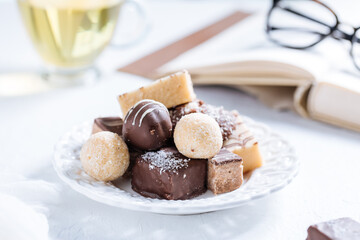 Combination of  sweet bites on a bright background with cup of tea, book and glasses 